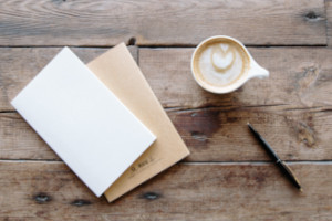 Cropped image of coffee and notebook on wooden table